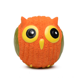 Squeaky ball shaped owl dog toy: has orange fur, yellow eyes, white pupils, yellow nose, green wings, and yellow feet.