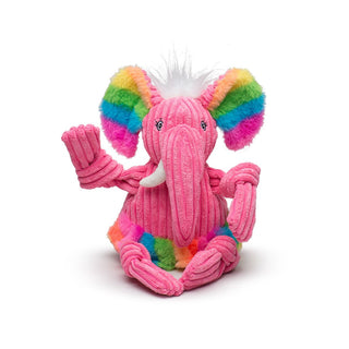 Large elephant shaped durable plush corduroy dog toy with squeakers, white hair, pink body and head, faux-fur rainbow inner-ear, pink trunk, white tusks, rainbow faux-fur tutu, knotted limbs.
