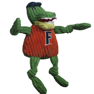 University of Florida Albert Gator durable plush dog toy: has green skin, has on a dark blue cap, black eyes, white pupils, plush-out mouth with white teeth, red mouth , light green jaw, has on a orange shirt with the university logo, and is squeaky with knotted limbs. Size large.