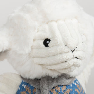 Close-up of a white plush lamb toy with a patterned scarf on a white background