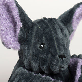 Close-up of Baxter Bat's face, showing black eyes, a stitched nose, and upright ears lined with soft, sparkly lavender fabric.