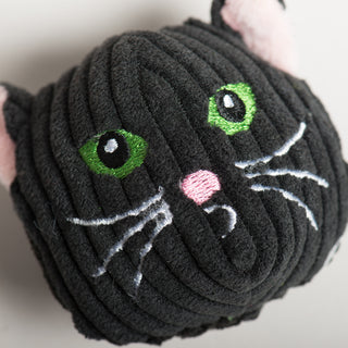 Top-down close-up of black cat Wee Huggles® Ball with green eyes, pink nose, and white whiskers.