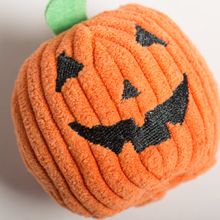 Top-down close-up of orange pumpkin Wee Huggles® Ball with stitched black Jack-o-lantern face and green stem.