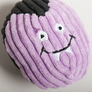 Top-down close-up of purple vampire Wee Huggles® Ball with white fangs and smiling expression.