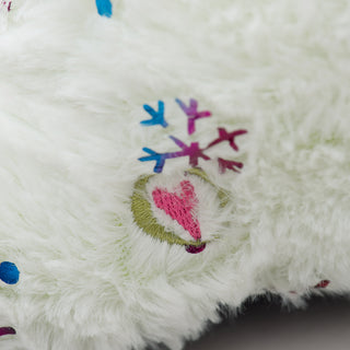 Close up view of HuggleHeart logo on white faux-fur narwhal plush dog toy.