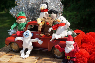 Lifestyle of set of six Santa's Workshop Wee Huggles sitting on toy truck.