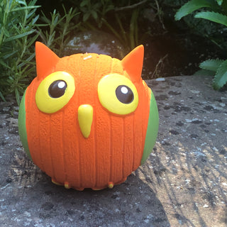 Owl squeaky ball dog toy with orange body, green feathers, and yellow feet, beak, and eyes.