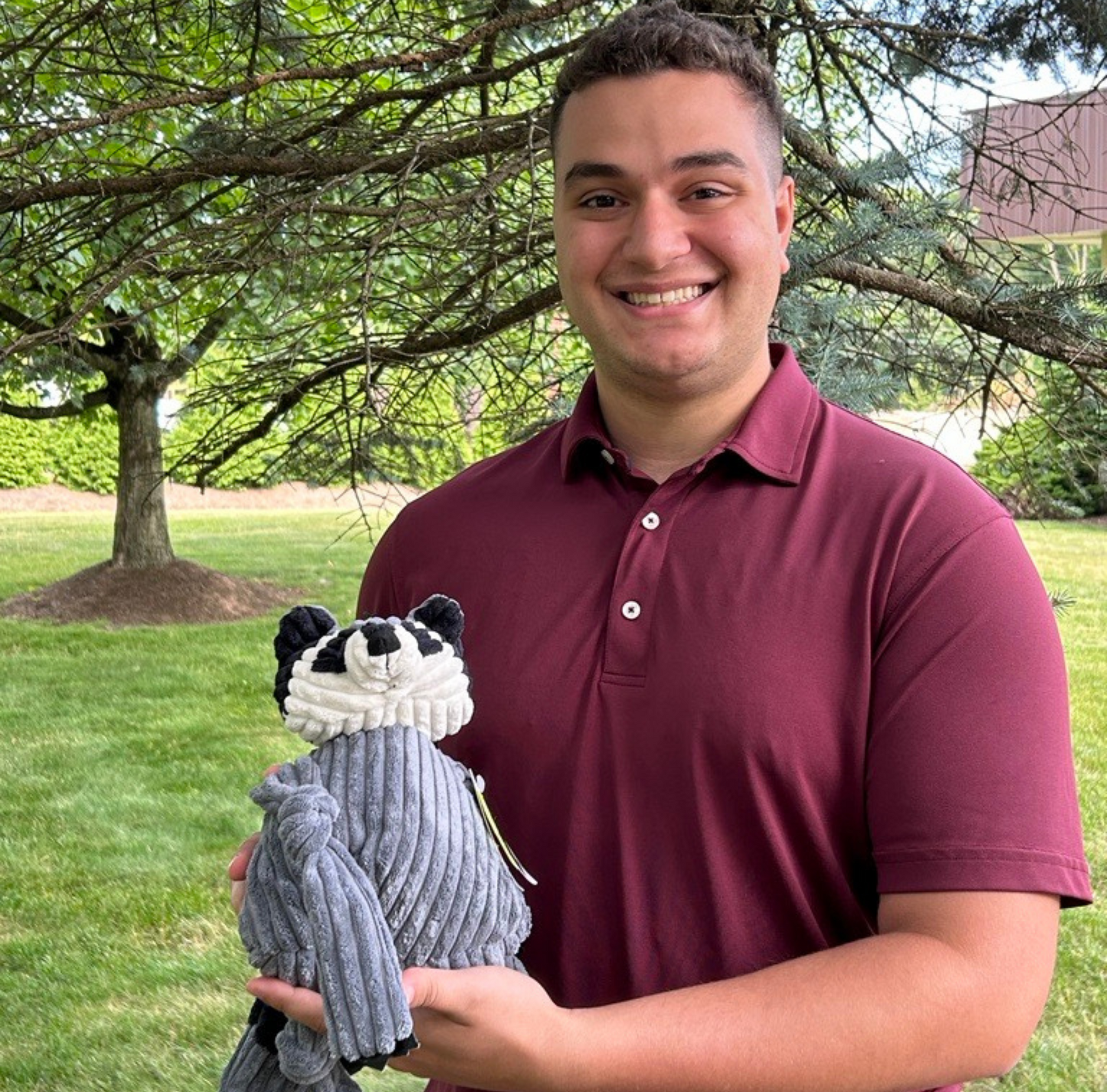 Lucas Kowalski, Financial Analyst, posed with Reggie Raccoon plush Knottie® toy