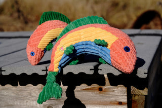 Set of two arched fish-shaped durable corduroy plush dog toys in large and small with knotted tails: green fins, peach, yellow, and blue stripes along body, and blue eyes.