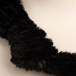 Close up image of dog shaped durable plush dog toy, has black fur, and it's knotted limb.