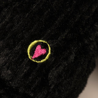 Close up image of dog shaped durable plush dog toy, with black fur, and HuggleHeart logo.