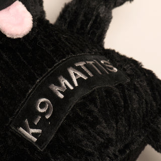 Close up image of dog shaped durable plush dog toy chest with the name "K-9 Mattis" written in silver.