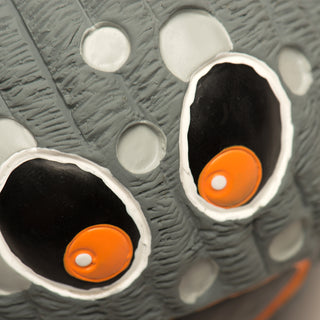 Close up of grey moon squeaky ball dog toy's big orange eyes.