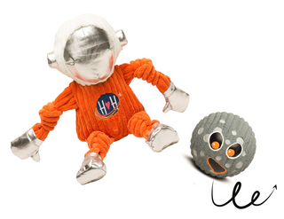 Set of two dog toys: large Astronaut plush dog toy in orange suit with HH logo on chest, white helmet, and silver face dome, gloves, and boots and large grey moon with big orange eyes and smile squeaky ball dog toy. Bouncy line underneath moon squeaky ball indicating that the moon ball bounces.