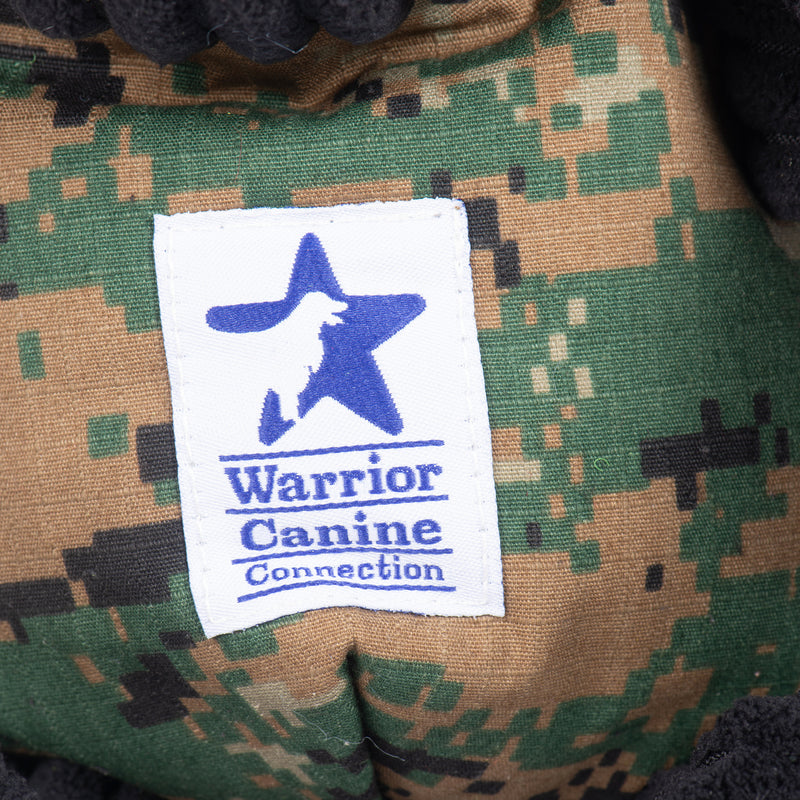 Close up of Warrior Canine Connection logo on camo body. Blue star with an open-mouthed dog in the middle.