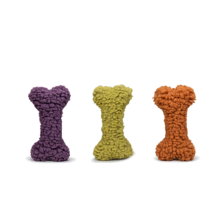 3 dog bones with colors of dark purple, orange, and olive. Each bone contains a squeaker and is coated with a furry layer of dense, synthetic lambswool.