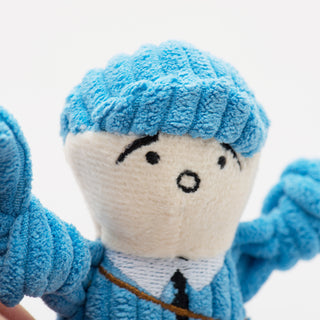 Close up of tiny plush corduroy dog toy mail carrier face with blue hat.