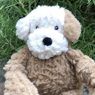 Close up view of Lulu's face to show fabric and embroidery detail sitting on grass.