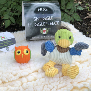 Set of three natural colored mat, squeaky ball shaped owl dog toy, duck shaped plush dog toy: Owl has orange fur, green wings, and yellow feet. Duck has brown hair, green head, yellow beak, brown neck, white stomach, gray-blue and blue knotted arms, and yellow knotted legs. Mat is in the size extra small and is in the color natural.