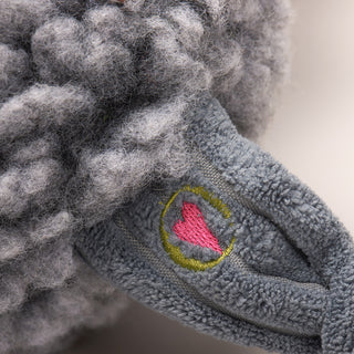 Close up image of elephant shaped durable plush dog toy leg that has the HuggleGroup logo on it.