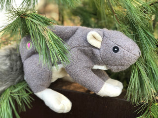 Lifestyle image of a plush squirrel dog toy on a wooden ledge.