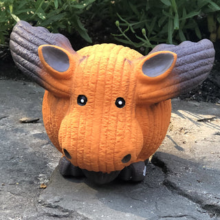 Orange moose squeaky latex ball dog toy with corduroy texture, brown antlers, beard, and feet, and black beady eyes sitting on rock.