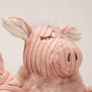 Close up image taken from the left of pig shaped plush dog toy face. Has a delighted facial expression, pink fur, and white hair.