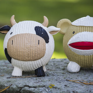 Set of two squeaky latex ball dog toys: The first is a cow with white fur, black spots, black nose, with white horns, inner-ear, and nose, next to a sock monkey, top of the head is white, has dark tan skin, and a white mouth.