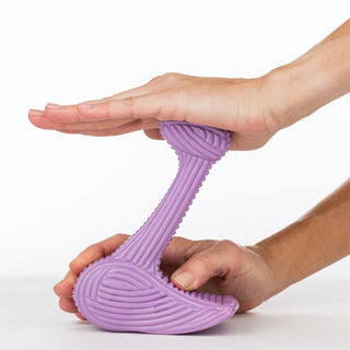 Purple bone dog chew toy made in the shape of an "L", with textured ridges all throughout the toy resembling corduroy texture. Toy is being pushed on to show that it is not flexible.