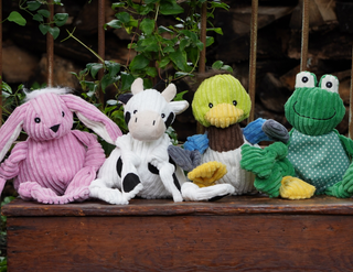 Pink Bunny, white cow, duck and green frog sitting on a woode bench