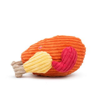 Side view of corduroy Giblets Plush Turkey dog toy with orange body, red wings, yellow drumsticks, and tan drumstick bones.