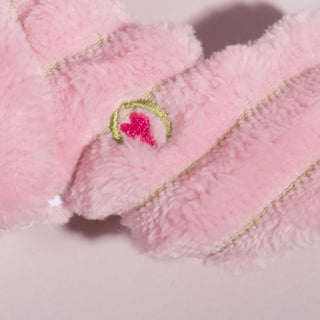 Close up view of HuggleHeart promise logo displayed on lightpink small axilotl plush dog toy.
