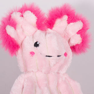 Close up view of small axolotl plush dog toy face. Has light pink fur skin, black eyes, whtie pupils, nice smile, dark pink rosey cheeks, and dark pink furred outer-ear. 