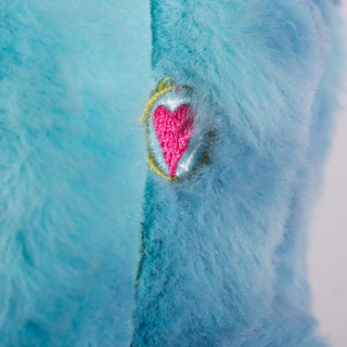 Close up view of the HuggleHeart promise on the octopus shaped, blue and fluffy plush dog toy. 
