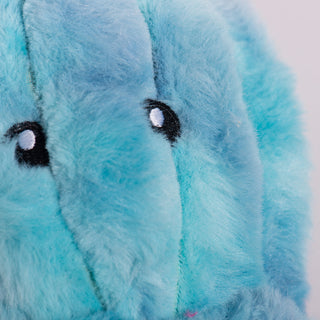 Close up view of the face on a octopus shaped plush dog toy with blue and soft fur. With black eyes and white pupils. 