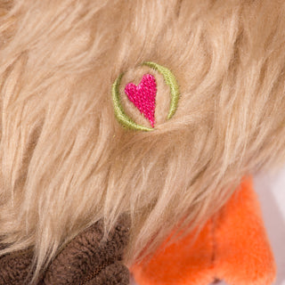 Close up view of HuggleHeart promise logo on duck shaped plush dog toy. 