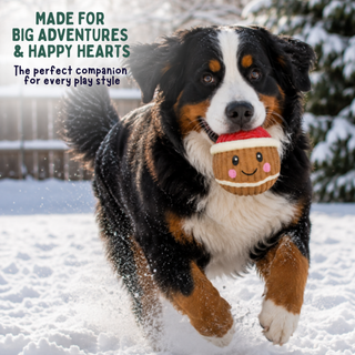 A Bernese mountain dog runs through the snow while holding a plush cookie toy in its mouth. Text in the upper left reads, 'MADE FOR BIG ADVENTURES & HAPPY HEARTS The perfect companion for every play style.