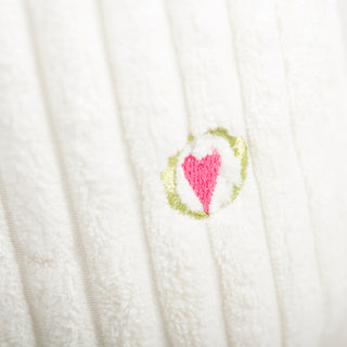Close-up of white plush toy showing embroidered pink heart detail
