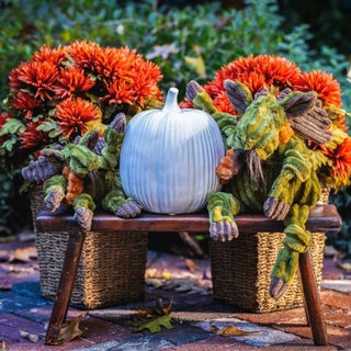Two Milo Moose Knottie toys posed on a rustic bench with smiling pumpkins and fall flowers in the background.

