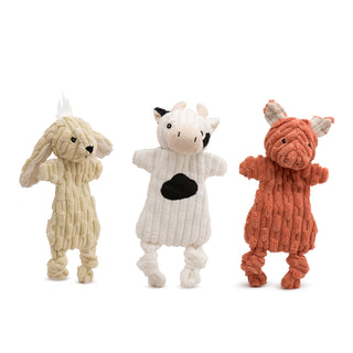 Set of three corduroy plush dog toys with minimal stuffing: pale yellow bunny with white inner ears and black embroidered facial details; white cow with black spots on chest and face, one black ear, beige snout, horns and inner ears, and black embroidered facial details; peach pig with white inner ears, and black embroidered facial details. All have knotted legs, minimal stuffing, crinkle paper, and a squeaker in the head.