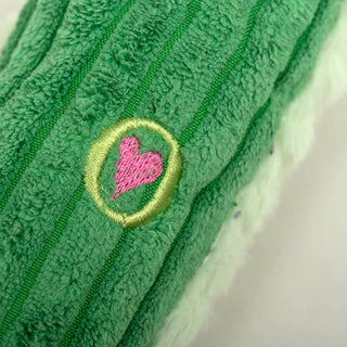 Close up of the HuggleHounds embroidered heart.  The heart is embroidered in hot pink and is inside a light green circle.  This heart indicates an authentic HuggleHound toy.