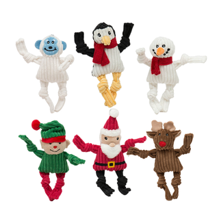 Six knotted dog toys shaped like animals and characters on a plain white background: a blue-faced monkey, a penguin with black wings and yellow legs, a snowman, an elf in green, a Santa Claus figure, and a brown reindeer.
