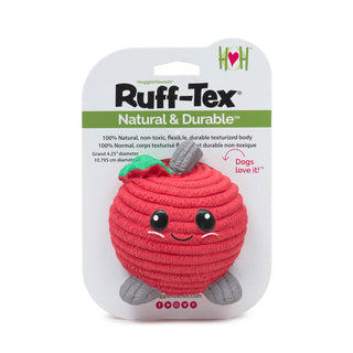 Large red apple-shaped latex squeaky ball dog toy with red corduroy texture, gray stem and feet, green leaf next to stem, big black eyes, cute black smile, and cute pink cheeks on header card packaging.