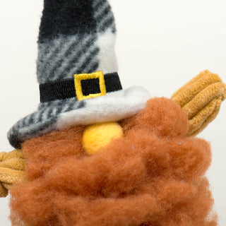 Close up of gnome face with burnt orange HuggleFleece® beard, yellow corduroy knotted arms, small round yellow nose sticking out of black and white plaid hat with gold buckle.