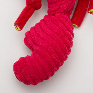 Close up image of lobster shaped durable plush dog toy claw: which is red and soft. 