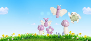 Desktop banner with blue sky, white clouds, green grass and flowers. With a set of 2 purple butterfly dog toys with white wings and a purple and white polka dot mushroom with a white stem .