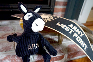 U.S. Military Academy Army mule durable plush corduroy dog toy sitting beside Army West Point pennant.