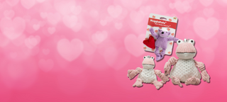 2025 Valentines day mobile banner. With a medium pink background with light pink hearts. Two pink and white furred plush frog dog toys, next to a purple squirrel plush cat toy.