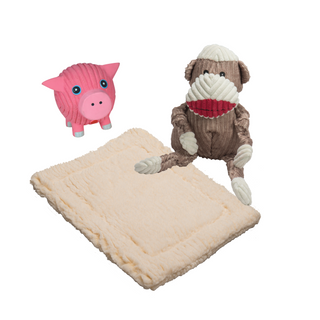 Large brown and white sock monkey durable corduroy plush dog toy with knotted limbs and large pink pig squeaky latex ball dog toy sitting on a natural cream colored HuggleFleece® dog mat.