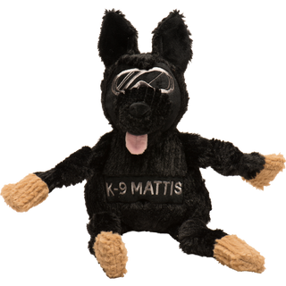 Black shepherd durable plush dog toy. Has black fur, has on a pair of silver goggles, black nose, pink tongue, black knotted limbs, light-brown paws, with the name "K-9 Mattis" across the chest, and is squeaky. 